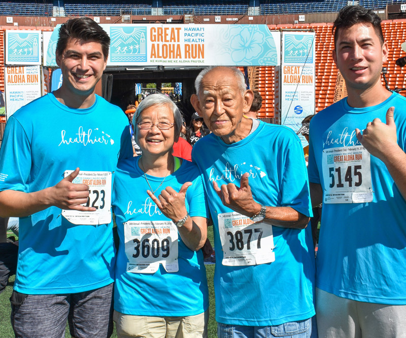man, daughter and two grown grandsons wave a shaka at the finish line of the Great Aloha Run