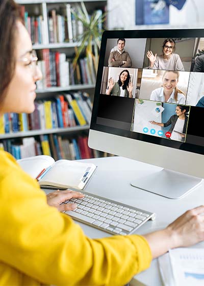Woman smiling while looking at virtual support group on computer monitor.