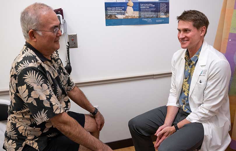 Male patient and doctor talking in exam room.