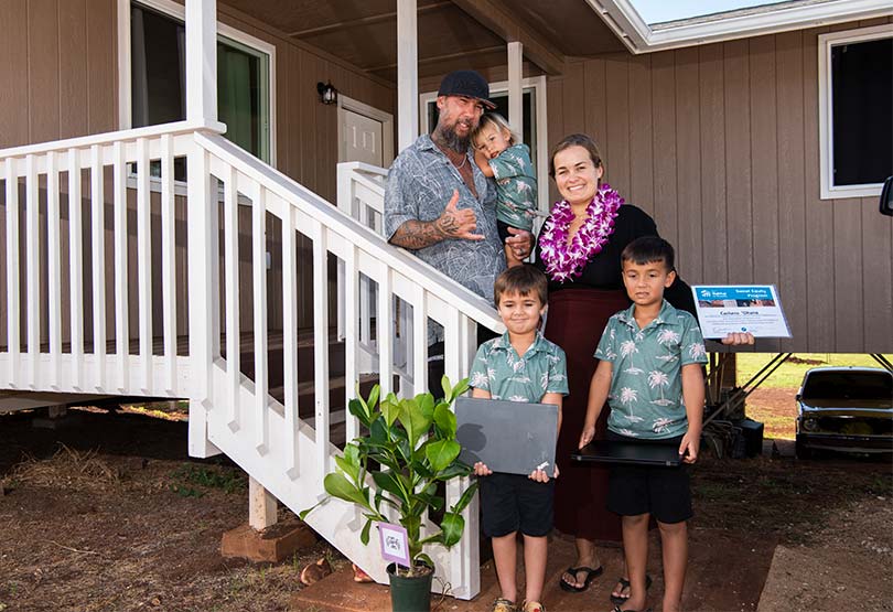 Couple with three children in front of their new home.