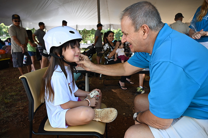 Doctor assisting girl with helmet fitting.