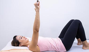 Woman laying on back doing exercise with arms upstretched.