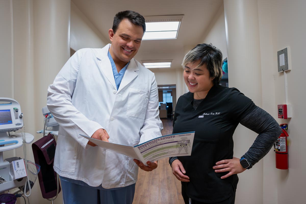 a doctor and nurse look over a brochure in a hallway