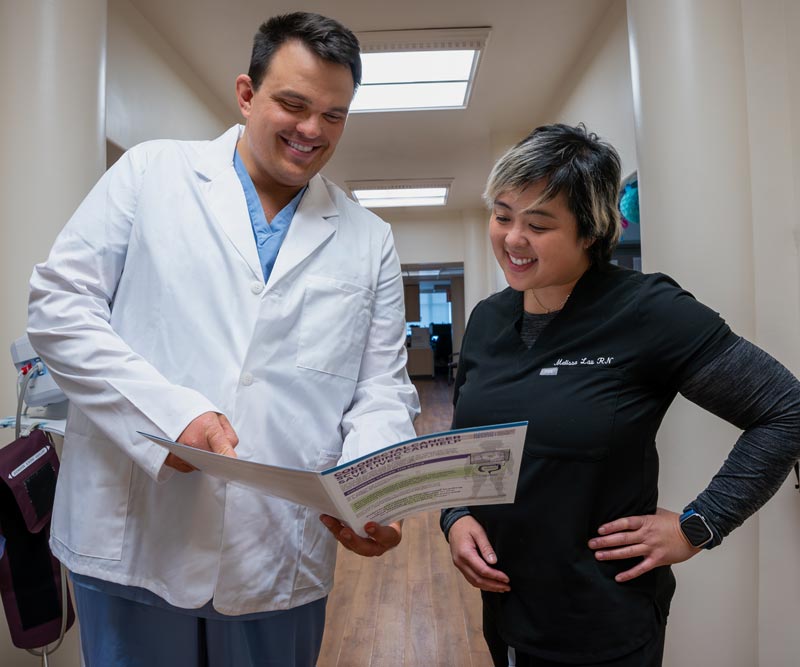 a doctor and nurse look over a brochure in a hallway