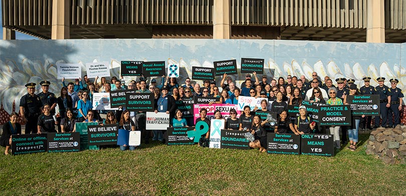 Large group shot of people holding signs about sexual assault awareness.
