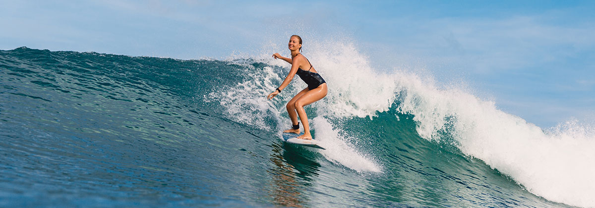 Smiling woman surfer on a small wave.