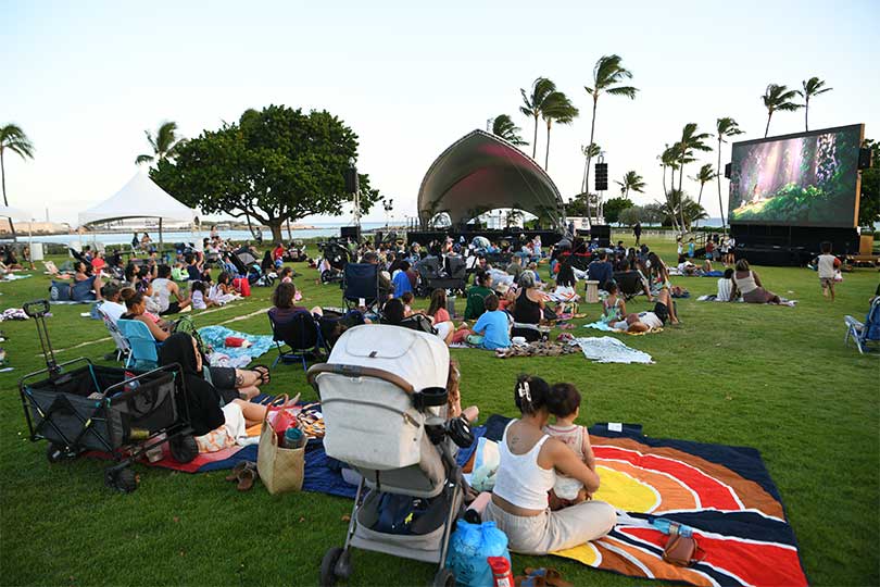 Families spread out on the lawn for a movie night by the lagoon.