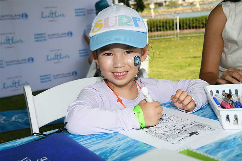 Youg girl with face paint smiling while coloring.
