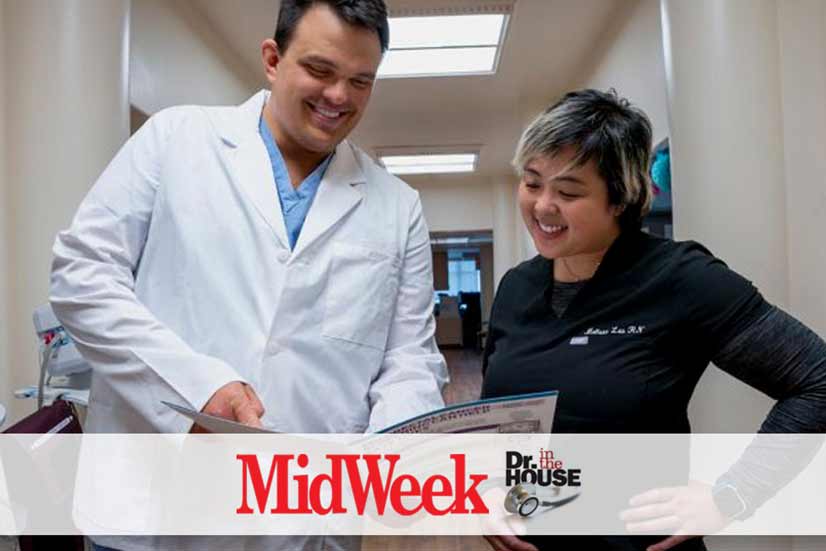 A doctor and nurse look over a brochure in a hallway.