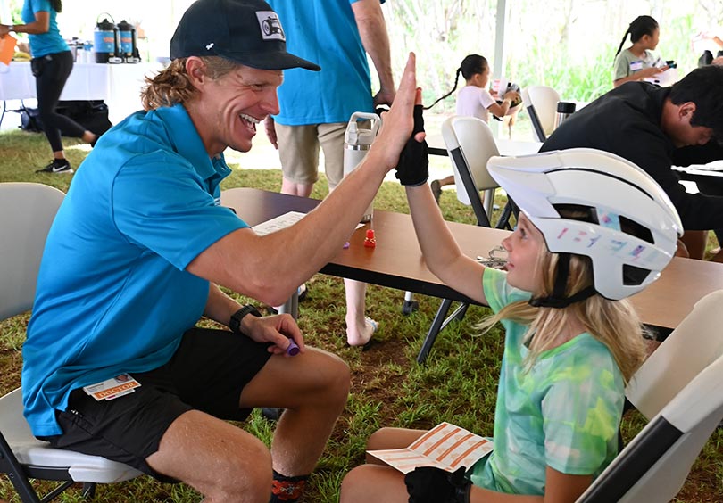 Doctor high fives a youngster he's just fitted with a bicycle helmet.