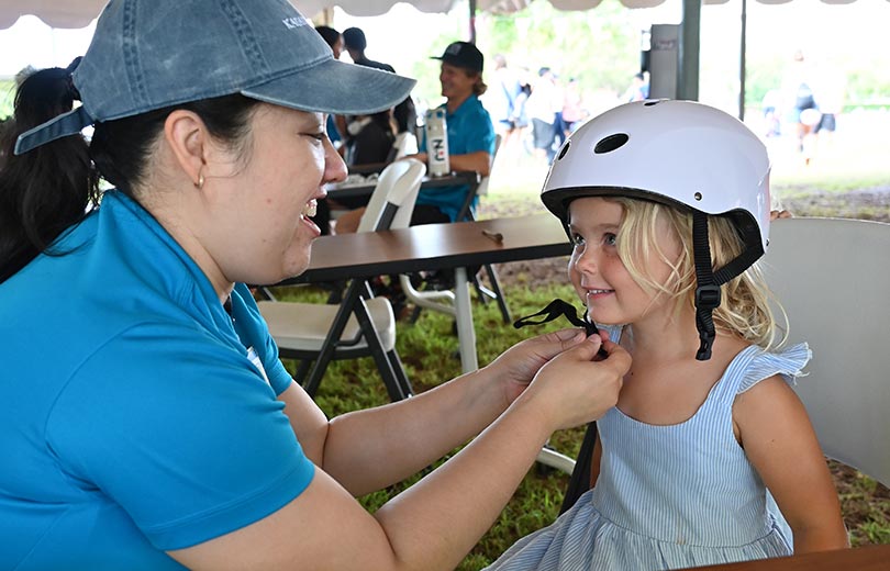 Smiling doctor fits a helmet onto a young child.