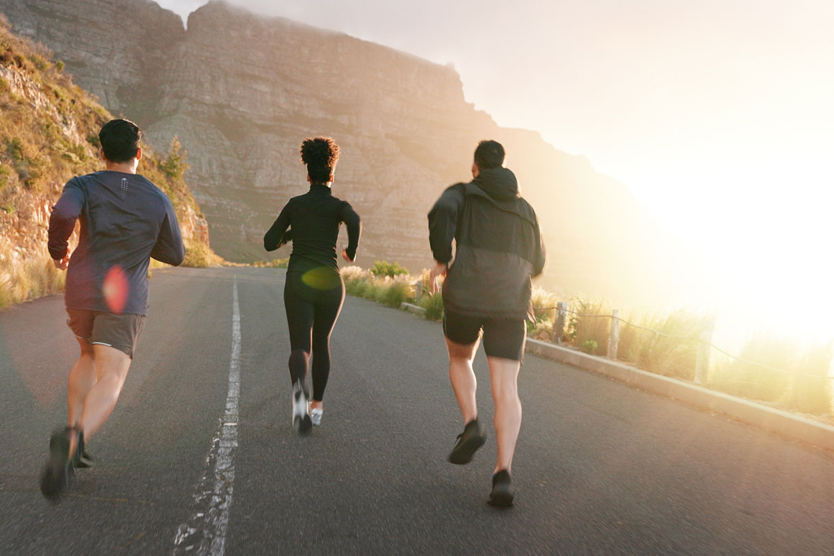 Three middle-aged people running up a paved road