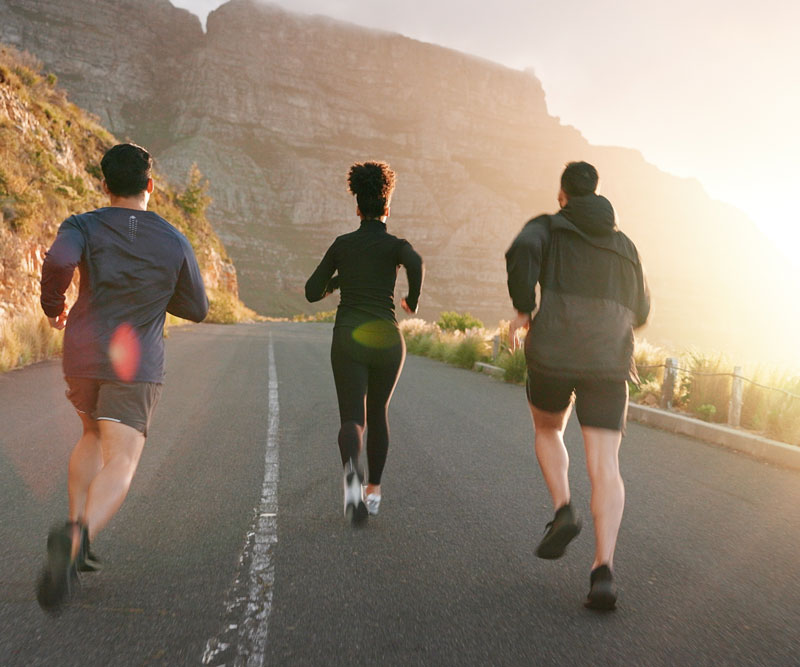 Three middle-aged people running up a paved road