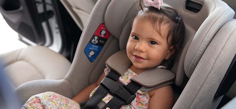 Smiling baby sitting in car seat.