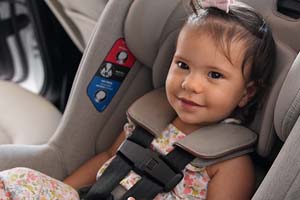 Smiling baby girl buckled in car seat.