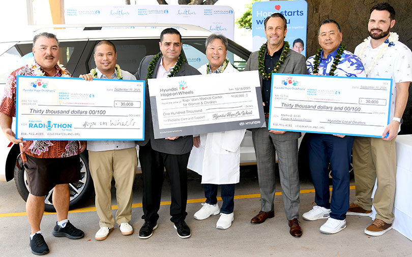 Group of people holding three giant donation checks.