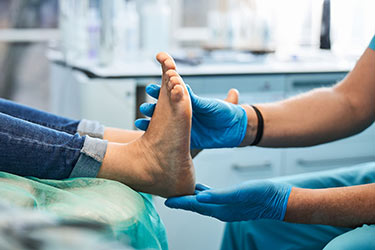 Doctor examining a bare outstretched foot.