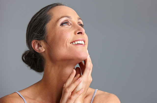 A woman with her hair in a bun looking up and smiling.