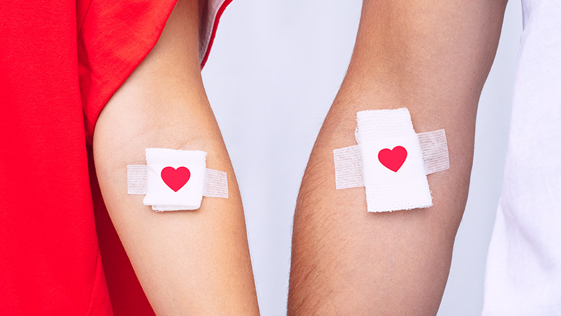 Arms of blood donors with a heart printed bandages.