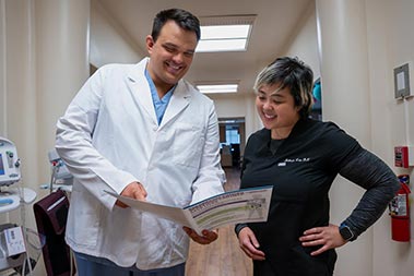 Two medical providers looking at a paper file in a clinic hallway.
