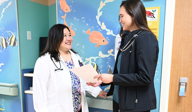 A doctor and pediatric resident talk in a hospital hallway