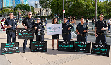 Community leaders and Honolulu police offers with signs promoting sexual assault awareness.