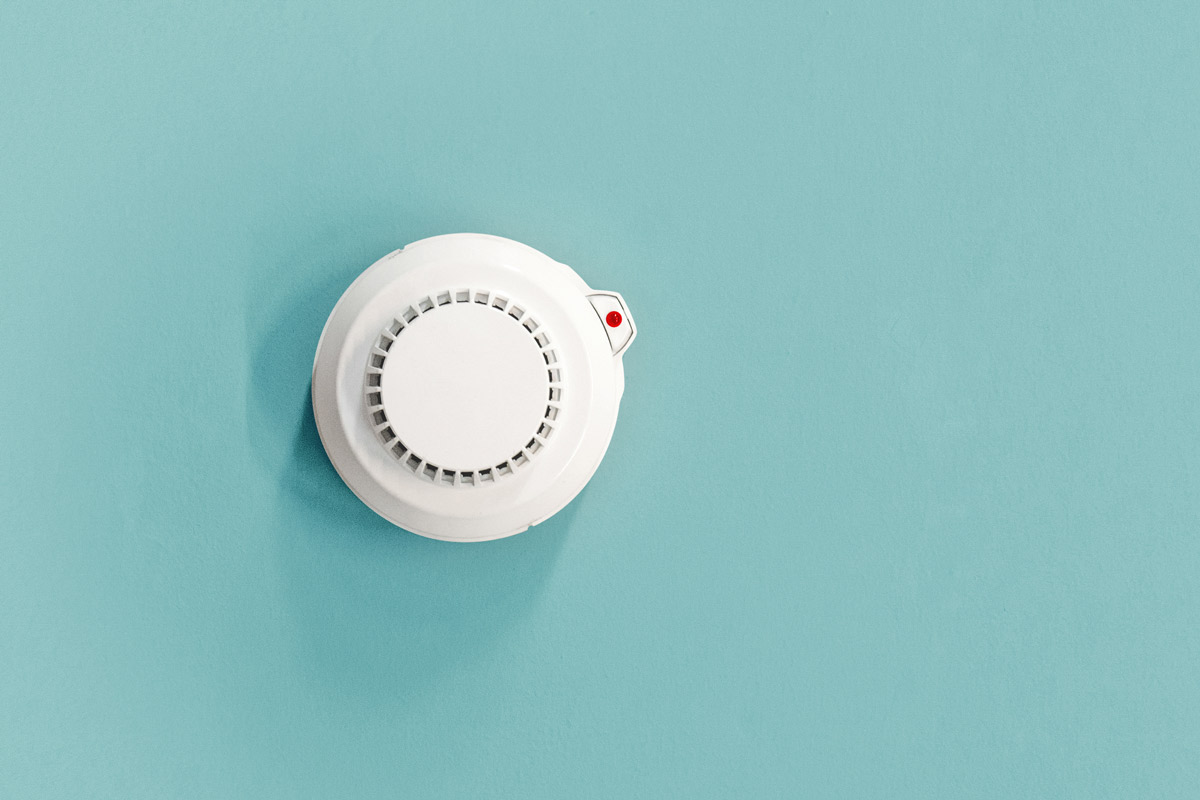 an overhead view of a smoke detector mounted on a teal ceiling