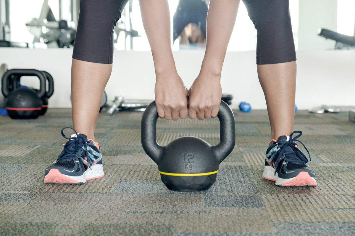 Athletic woman bending over to pick up a kettlebell